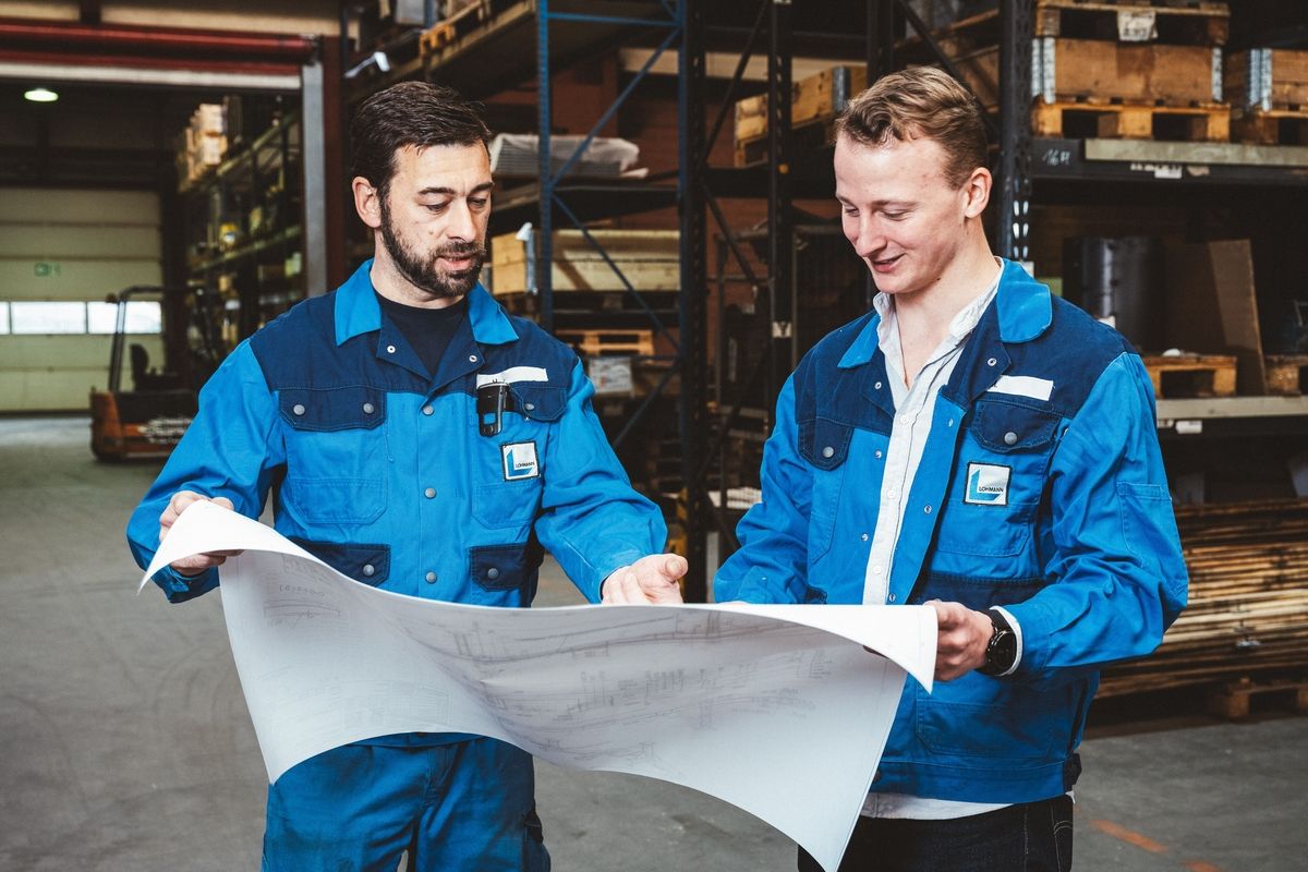 Zwei Mitarbeiter betrachten einen Bauplan